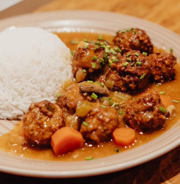 Photo plate de boulettes de viande avec du riz et des carottes dans la sauce