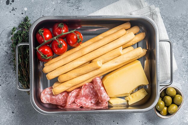 Plateau d'apéritif avec bâtonnets de pain grissini salami tomate et parmesan Bakground gris Vue de dessus