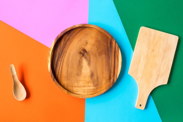 Plateau en bois et cuillère en bois sur fond coloré.