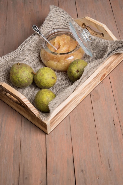 Plateau en bois avec un pot de purée de poires et de poires fraîches sur fond clair Orientation verticale