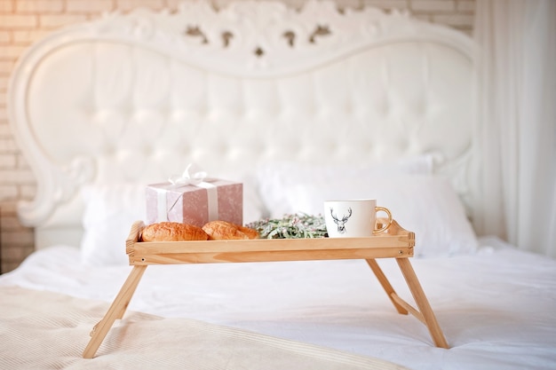 plateau avec café, croissants et un cadeau sur le lit