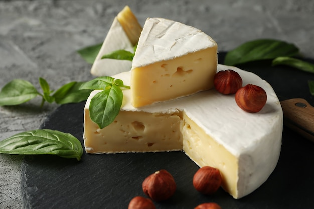 Plateau avec camembert, noisette et basilic sur fond gris