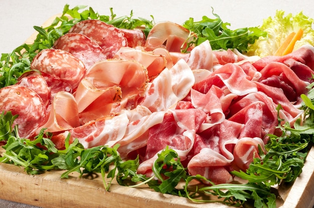 Photo un plateau de délicieux jambons de prosciutto mélangés et de salami avec de la laitue