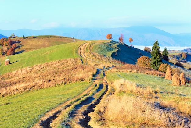 Plateau du matin brumeux d'automne avec pile de foin et route sale de campagne (périphérie du village de Mighgirya, Mont des Carpates, Ukraine).