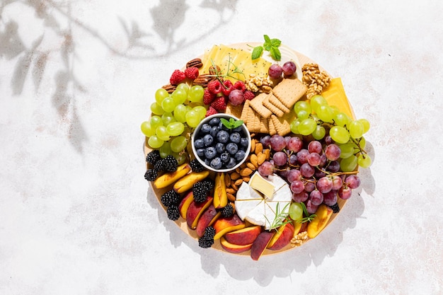 Plateau de fromages d'automne avec fruits frais et baies servis avec vue de dessus de vin blanc