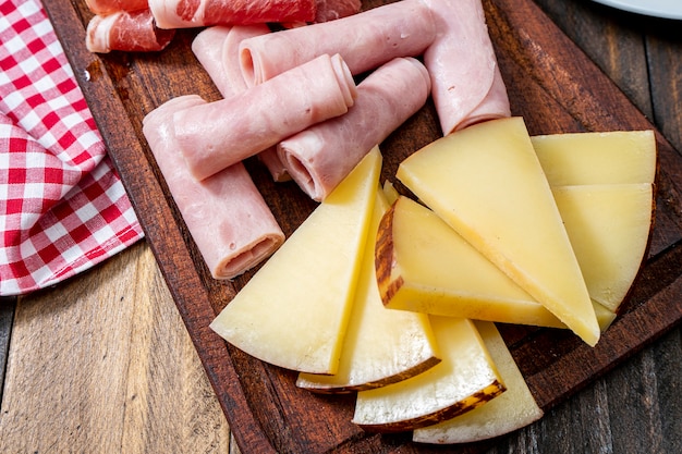 Plateau de fromages et charcuterie sur une table en bois. Vue zénithale ou à vol d'oiseau.