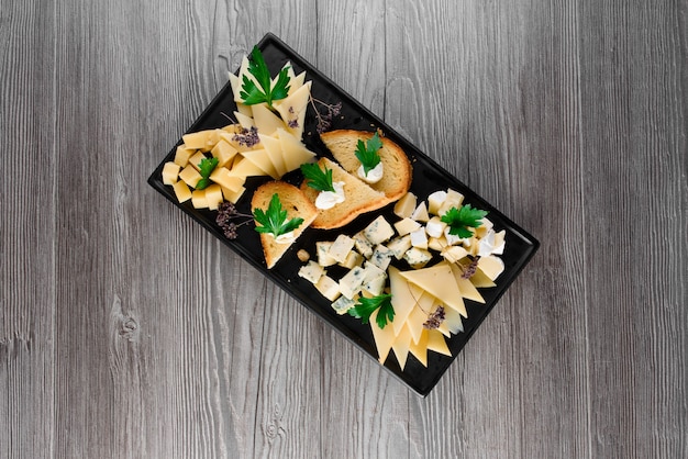 Plateau de fromages avec de délicieux fromages, noix. Parmesan, confiture, dorblu sur la plaque noire. Apéritif alimentaire du restaurant.