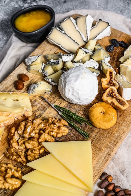 Plateau de fromages avec fromages bio français, figues, noix sur fond gris. Vue de dessus. Entrée savoureuse au fromage