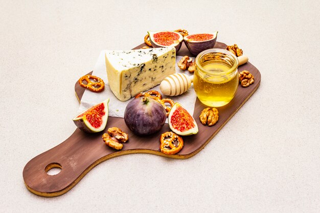 Plateau de fromages (planche) avec fromage bleu, miel, noix, figues, bretzels