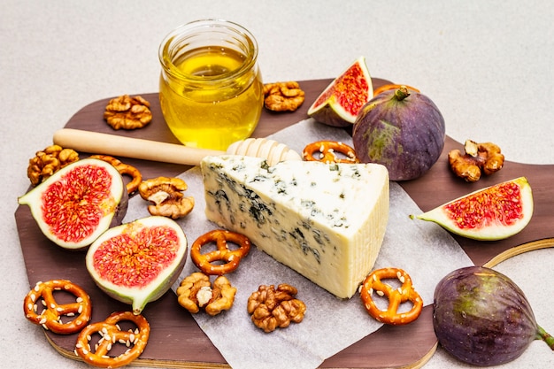 Plateau de fromages (planche) avec fromage bleu, miel, noix, figues, bretzels