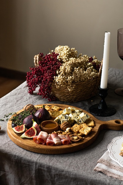 Plateau de fromages servi avec de la confiture de raisins figues craquelins et noix sur nappe en lin vertical