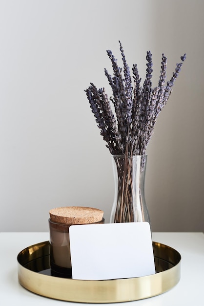 Plateau en métal avec bougie aromatique fleurs de lavande séchées dans un vase et carte papier vierge