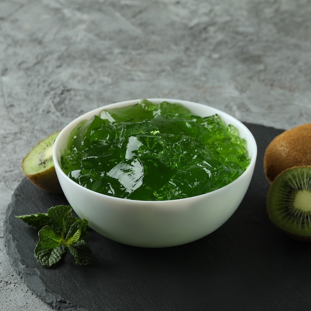 Plateau noir avec bol de gelée de kiwi sur table texturée gris