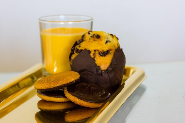 Un plateau de nourriture avec un verre de jus d'orange et un cookie aux pépites de chocolat.