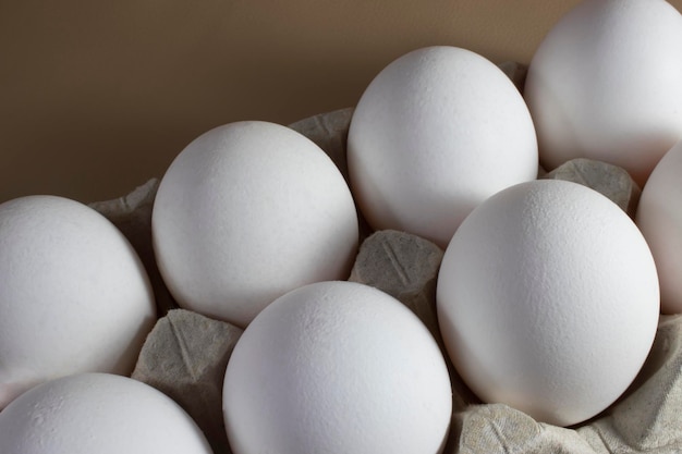 Un plateau d'œufs blancs frais en gros plan sur une forme de carton