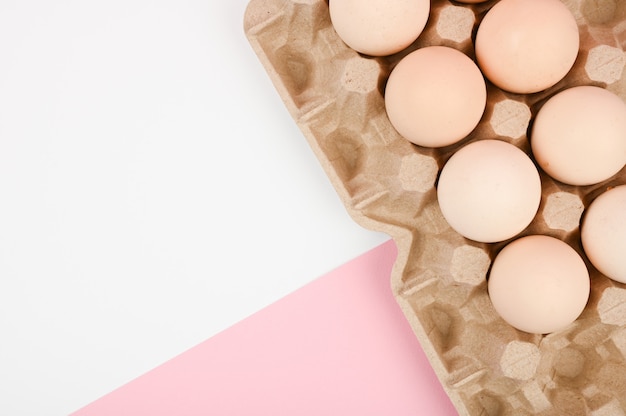 Un plateau d'oeufs sur fond blanc et rose. plateau écologique avec testicules. tendance minimaliste, vue de dessus. Plateau d'oeufs. Concept de Pâques.