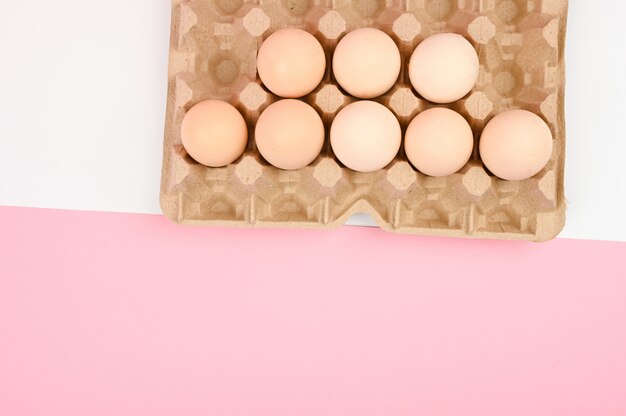 Photo un plateau d'oeufs sur fond blanc et rose. plateau écologique avec testicules. tendance minimaliste, vue de dessus. plateau d'oeufs. concept de pâques.