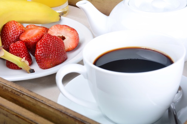 Plateau de petit-déjeuner avec café et fruits.