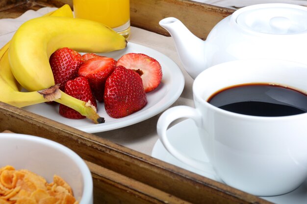 Plateau de petit-déjeuner avec café, jus d&#39;orange, céréales et fruits.