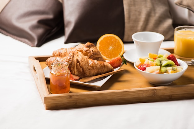 Plateau avec petit-déjeuner sur le lit à l'intérieur d'une chambre