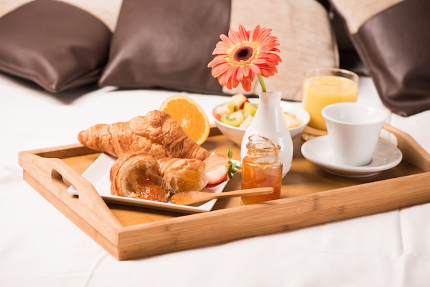 Plateau avec petit-déjeuner sur le lit à l'intérieur d'une chambre