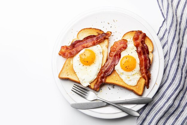 Photo plateau de petit déjeuner avec des œufs frits, du bacon et des toasts.