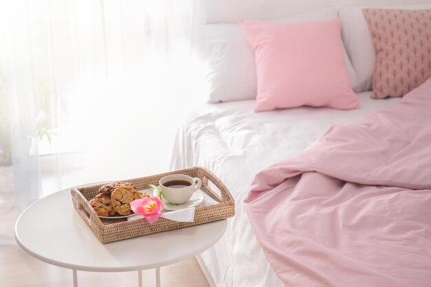 Plateau avec petit-déjeuner savoureux et tulipe sur table près du lit