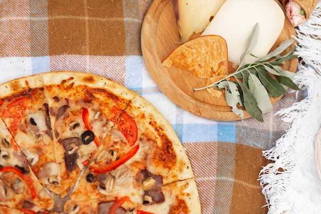 Plateau de pizza et fromage sur un couvre-lit à carreaux.