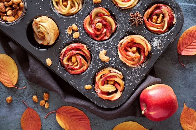 Plateau de roses pomme cuites au four dans une pâte feuilletée sur fond texturé gris