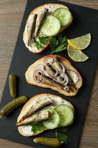 Plateau avec des sandwichs aux sprats sur fond de bois