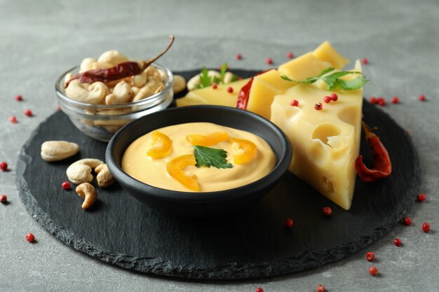 Plateau avec sauce au fromage et ingrédients sur une table texturée grise