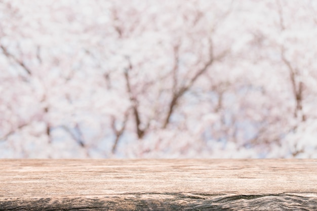 Plateau de table en bois vide et arbre fleuri flou de sakura