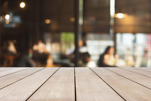 Plateau de table vide en bois et arrière-plan flou dans un café avec des gens assis et buvant du café l'après-midi au restaurant Maquette pour l'affichage du produit