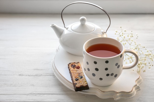 Plateau avec tasse de thé et barre de céréales sur la table Petit-déjeuner savoureux