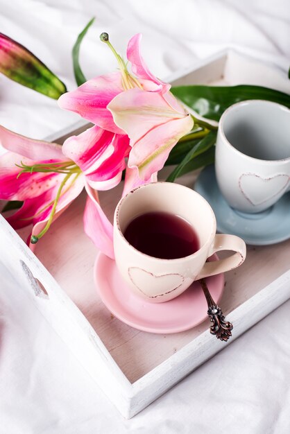 plateau avec une tasse de thé chaud dans le lit