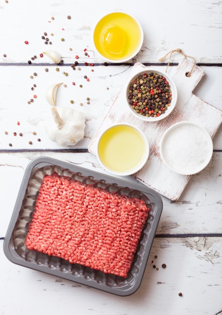 Photo plateau avec de la viande de boeuf hachée crue maison avec des épices et des herbes. vue de dessus.