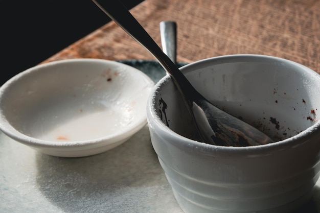 Des plats en céramique de dessert vides sur une assiette blanche avec une cuillère d'argent en gros plan