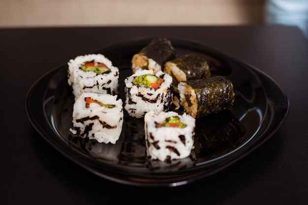 Plats végétaliens Cuisine japonaise Sushi et petits pains Livraison de nourriture à la maison Deux portions de petits pains végétaliens sur des assiettes noires se trouvent sur la table Nourriture conceptuelle