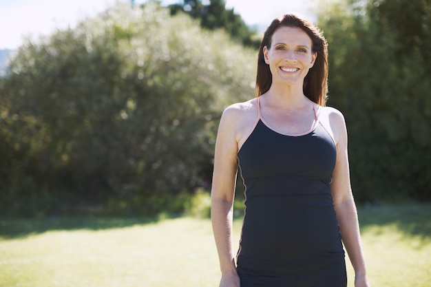 Le plein air est un lieu de repos pour elle Une jolie femme en vêtements de sport souriant debout à l'extérieur