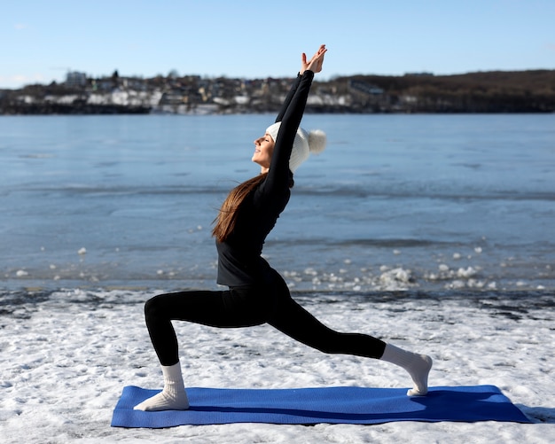 Plein coup femme faisant du yoga par temps hivernal