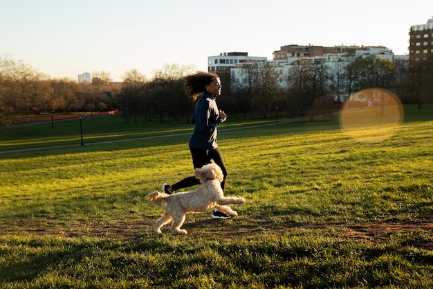 Plein coup femme qui court avec un chien à l'extérieur