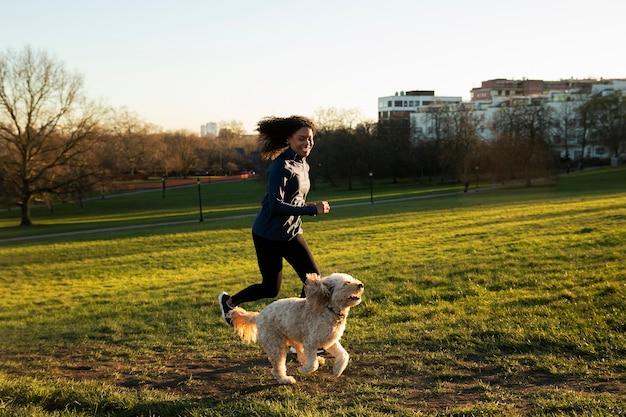 Plein coup femme qui court avec un chien à l'extérieur