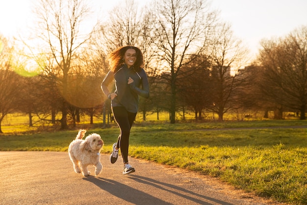 Plein coup femme qui court avec un chien à l'extérieur