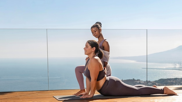 Photo plein coup de femmes heureuses faisant du yoga sur tapis