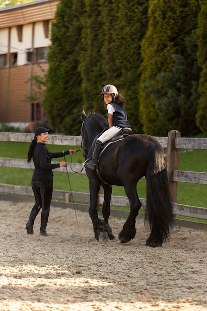 Plein coup fille apprenant à monter à cheval