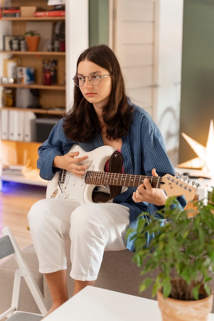 Photo plein coup fille jouant de la guitare à la maison