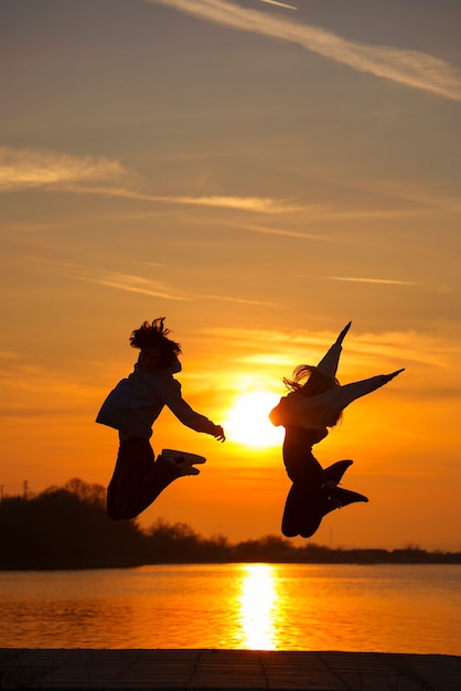 Photo plein coup de gens sautant au coucher du soleil