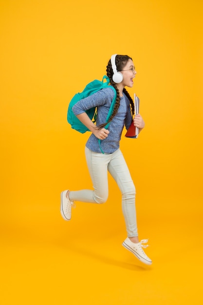 Plein d'énergie Enfant énergique courir à l'école Fille heureuse en mouvement sur fond jaune Énergie de l'enfance Maintenir l'énergie cinétique École et éducation Apprentissage actif Être dans une énergie positive