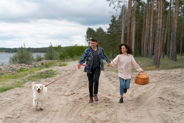 Photo plein de gens marchant avec un chien sur la plage