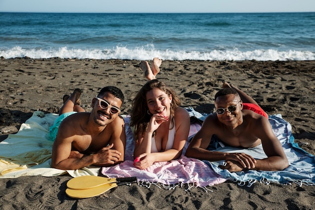 Plein de gens souriants allongés sur la plage